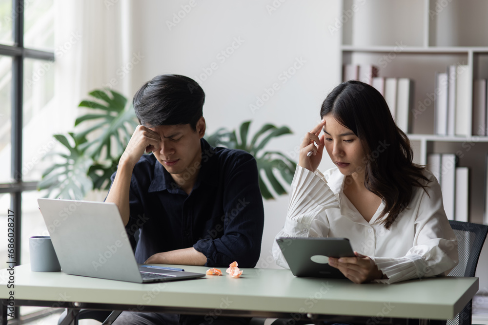 Two young asian businessman and woman are sitting stressed out with work in the office. Two young asian businessman and woman are sitting stressed out with work in the office.