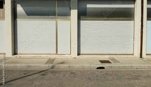 Old abandoned shop with white washed store windows at the road side. Concrete sidewalk and street in front. Background for copy space.