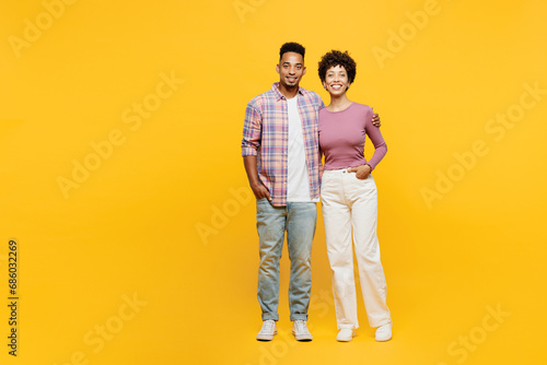 Full body smiling happy cool young couple two friends family man woman of African American ethnicity wear purple casual clothes together stand hug looking camera isolated on plain yellow background. © ViDi Studio