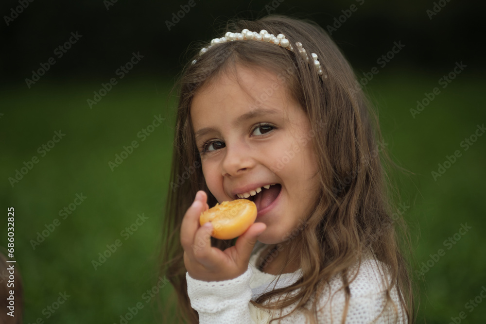 joyous girl bites into a fresh apricot, her smile radiating delight, amidst a verdant backdrop. The image echoes the focus on sustainable living and farm-to-table eating trends. joyous girl bites into a fresh apricot, her smile radiating delight, amidst a verdant backdrop. The image echoes the focus on sustainable living and farm-to-table eating trends.