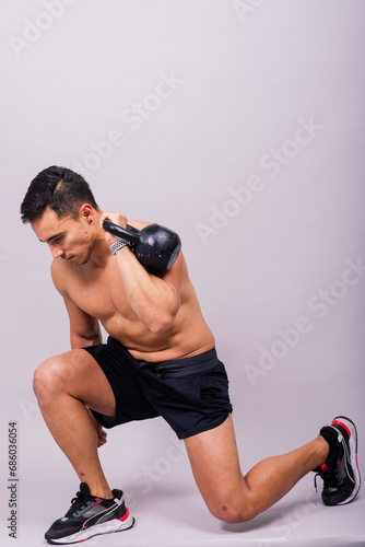 Handsome muscular man holding kettle bell with copy space. Hispanic male athlete © Ivan Zelenin