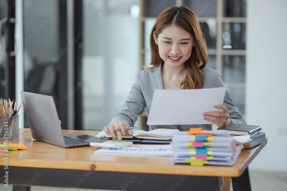 Businesswoman working with stack of documents papers and laptop sitting at office desk. Businesswoman working with stack of documents papers and laptop sitting at office desk.