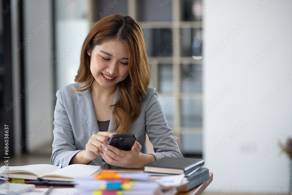 Accounting asian woman use smartphone and laptop at office desk in office, Accounting businesswoman online working concept. Accounting asian woman use smartphone and laptop at office desk in office, Accounting businesswoman online working concept.