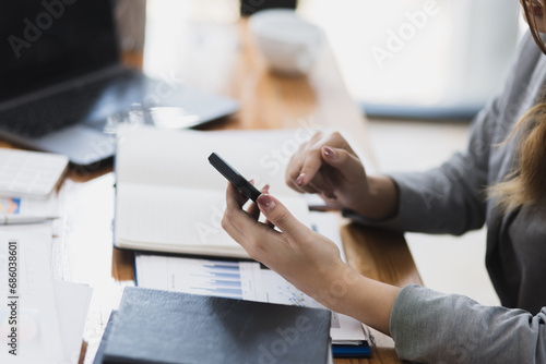 Accounting asian woman use smartphone and laptop at office desk in office  Accounting businesswoman online working concept.