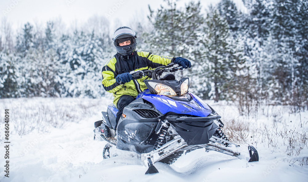 Man is riding snowmobile in mountains. Pilot on a sports snowmobile in a mountain forest. Athlete rides a snowmobile in the mountains. Snowmobile in snow. Concept winter sports Man is riding snowmobile in mountains. Pilot on a sports snowmobile in a mountain forest. Athlete rides a snowmobile in the mountains. Snowmobile in snow. Concept winter sports