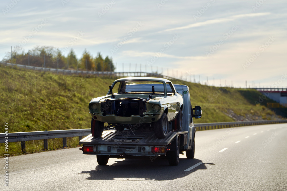 Recover a Retro Car After an Accident. A Project to Restore a Classic Car with the Help of a Tow Truck. A Vintage Car Damaged by a Collision on the Highway.