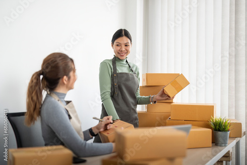 Small business SME owner, Two young Asian business owner woman prepare parcel box and check online orders of product for deliver to customer, packaging, Shopping Online concept