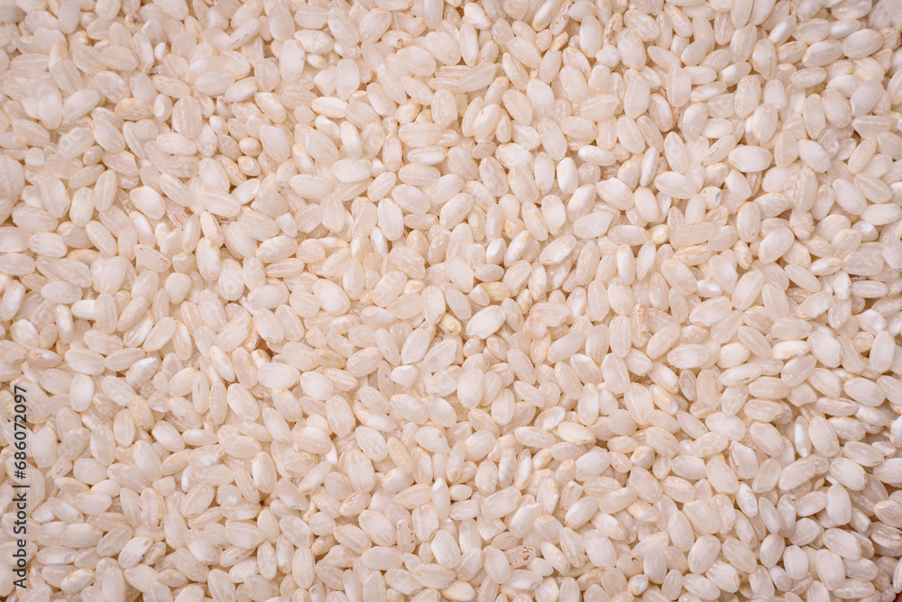 White uncooked rice in a round ceramic bowl on a dark concrete background White uncooked rice in a round ceramic bowl on a dark concrete background