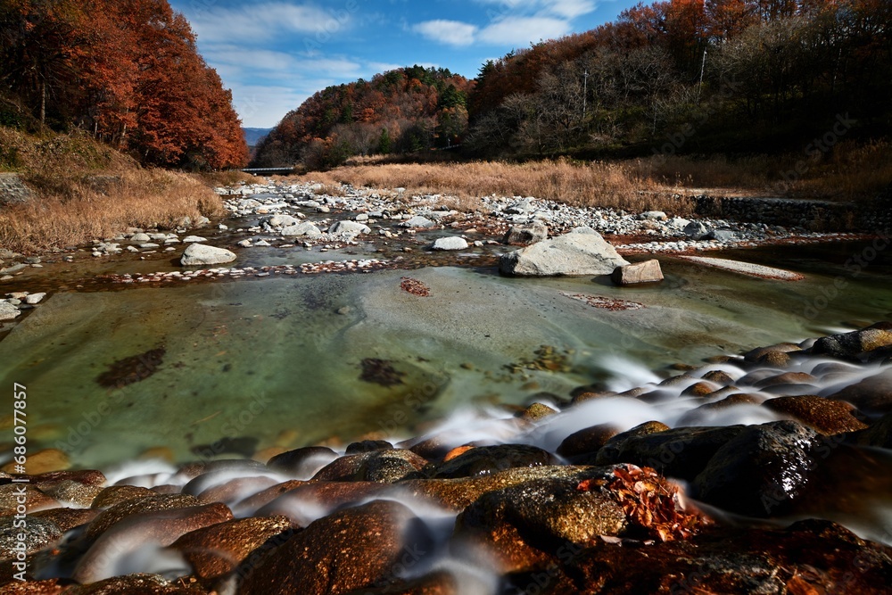 Naklejka premium Golden Autumn Foliage in red and orange colors with beautiful lake view background under the blue sky in Japan