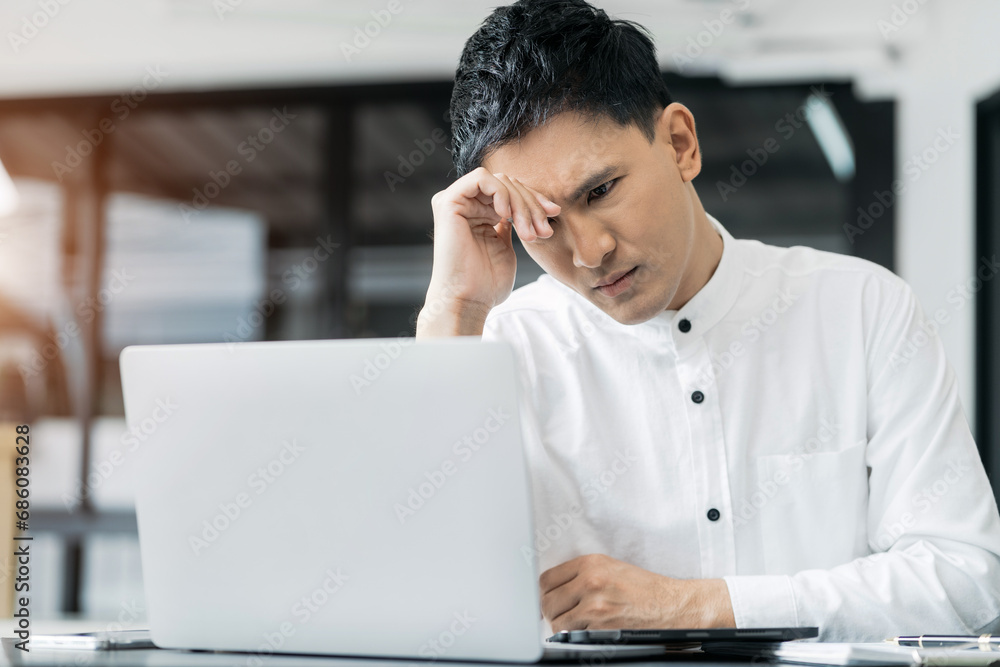 Fototapeta premium Young stressed Asian businessman working in the office. Businessman thinking too much work concept in the office.