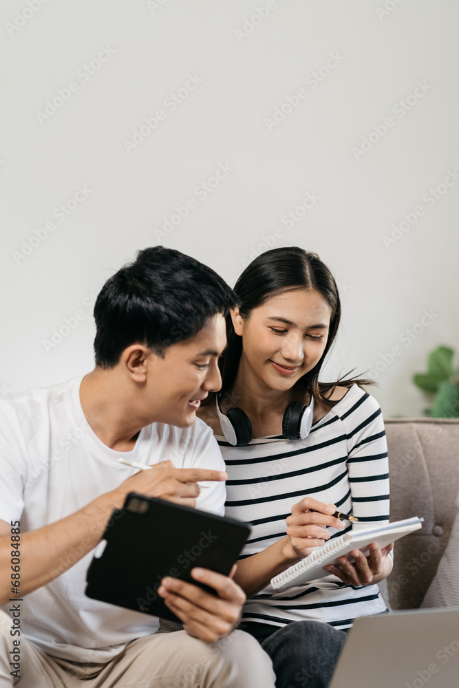 Asian couple relaxing with smartphone at home, loving man and woman sitting on couch together, Browsing Internet on mobile phone and laptop. Asian couple relaxing with smartphone at home, loving man and woman sitting on couch together, Browsing Internet on mobile phone and laptop.