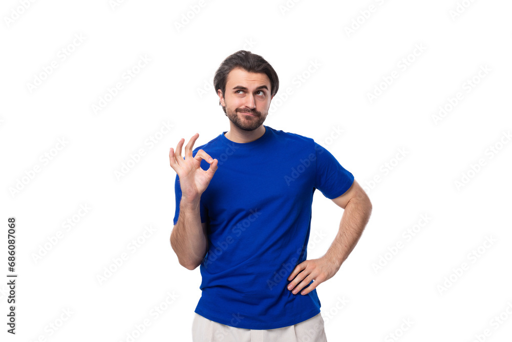 young handsome brunette man with a beard in a blue t-shirt actively gesturing with his hands on a white background with copy space young handsome brunette man with a beard in a blue t-shirt actively gesturing with his hands on a white background with copy space