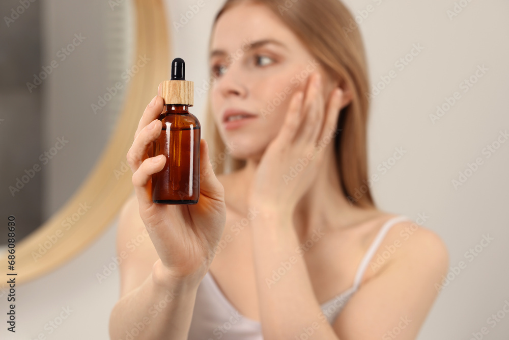 Fototapeta premium Woman with bottle of essential oil indoors, selective focus. Space for text