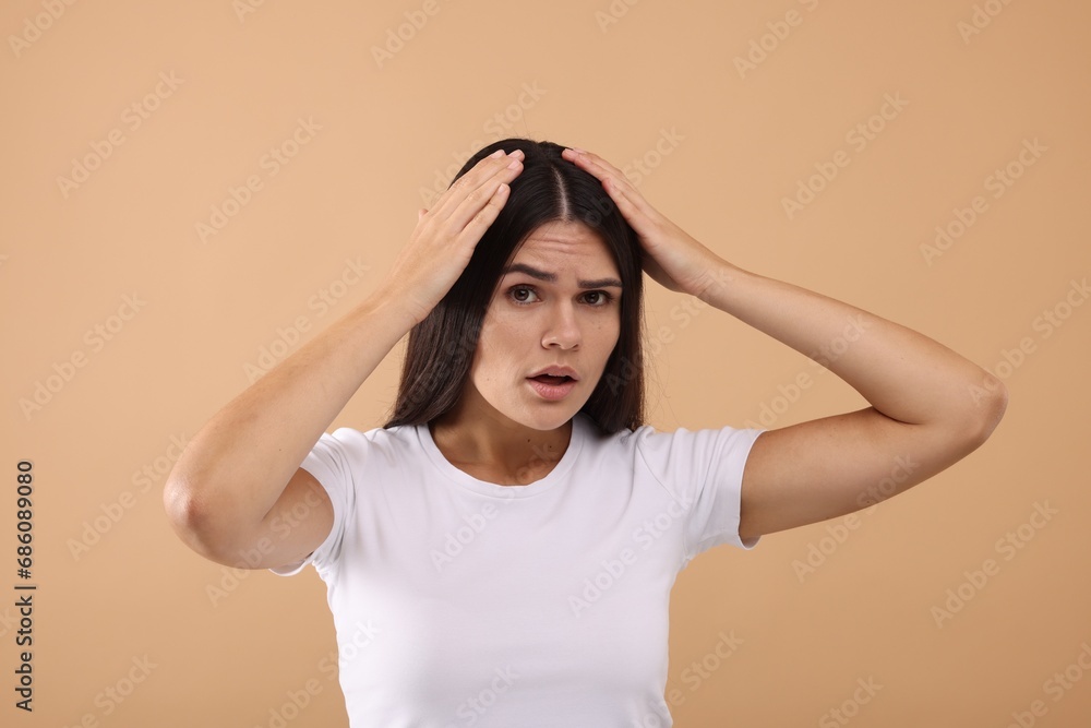 Emotional woman examining her hair and scalp on beige background Emotional woman examining her hair and scalp on beige background