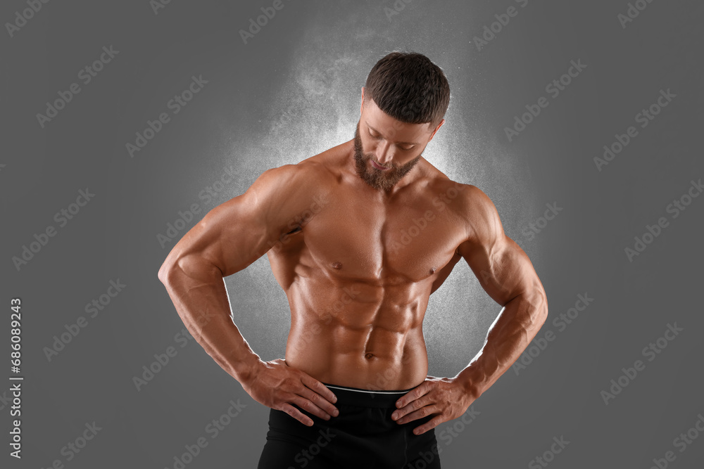 Young bodybuilder with muscular body on grey background
