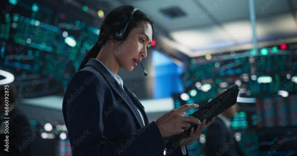 Professional Stock Exchange Trader Working with Serious Focused Attitude. Female Stockbroker Talking with Business Clients on a Call, Working on Tablet, Day Trading Shares for Business Clients Professional Stock Exchange Trader Working with Serious Focused Attitude. Female Stockbroker Talking with Business Clients on a Call, Working on Tablet, Day Trading Shares for Business Clients