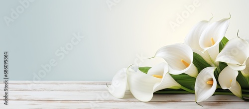 White calla flowers on a white wooden table, with room to write.