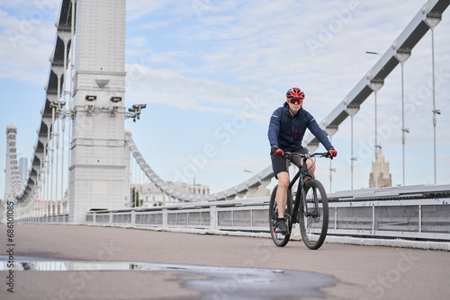 Man riding on bicycle across the bridge in the city.