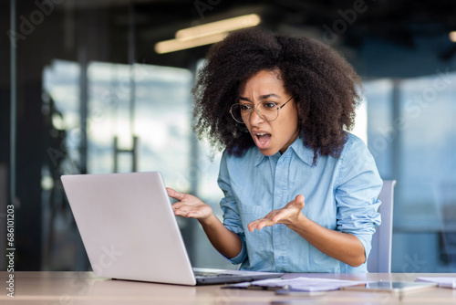 Woman at the workplace inside the office is not satisfied with the work of the computer, a frustrated businesswoman is shouting at a broken laptop, and overpriced broken software