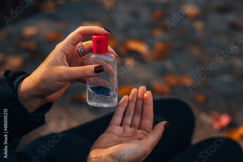 Epidemics of coronavirus and infectious diseases. Close-up of a woman using antibacterial hand sanitizer while sitting on a park bench. Prevention of influenza. 