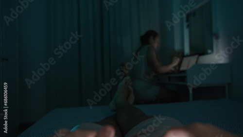 POV. Marital Bedroom, Woman scolds the man for lying around doing nothing and playing video games on his smartphone. He flips her the middle finger and continues playing. Mock up. photo