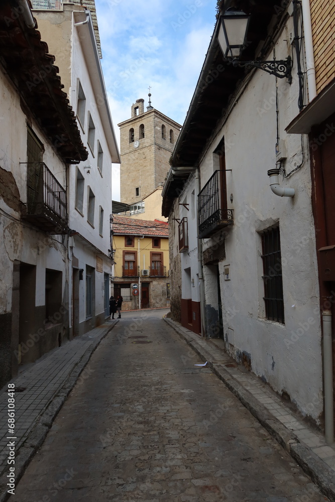 Cebreros, Avila, Spain, November 28, 2023: Narrow street with the church bell tower in the background of the town of Cebreros, Avila, Spain