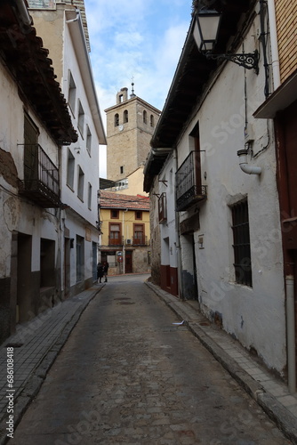 Cebreros, Avila, Spain, November 28, 2023: Narrow street with the church bell tower in the background of the town of Cebreros, Avila, Spain © Marco Gallo