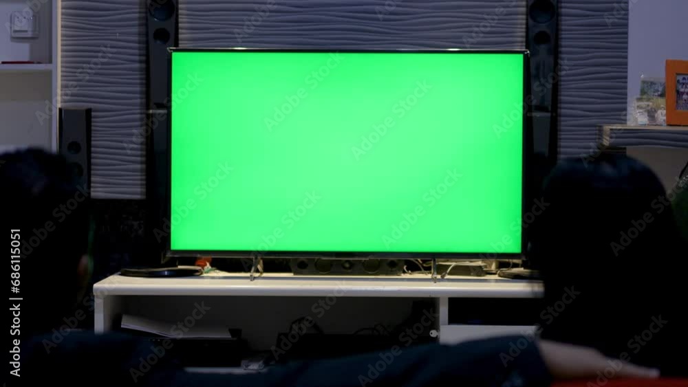 Family Couple Watches Green Screen TV Mockup Sitting on Couch in Living Room Together. Rear View on Casual People who Watching TV Green Screen in Domestic Cinema. Looking TV Show or News in Home Family Couple Watches Green Screen TV Mockup Sitting on Couch in Living Room Together. Rear View on Casual People who Watching TV Green Screen in Domestic Cinema. Looking TV Show or News in Home