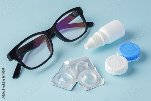 Eyeglasses and contact lenses with container on blue background