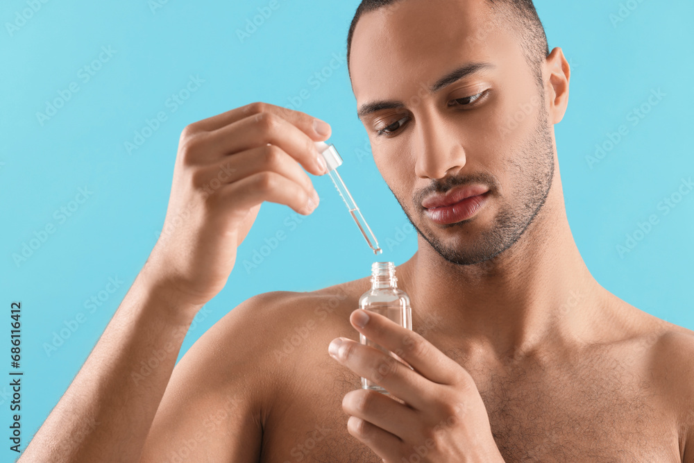 Handsome man with cosmetic serum in hands on light blue background Handsome man with cosmetic serum in hands on light blue background