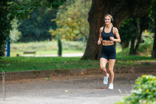 Sporty blonde runner woman running in park.