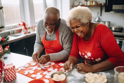 Joyful senior African-American couple cooks Christmas dinner at home. Happy black wife and husband prepare delicious food for family holiday. Positive people at table with treats in kitchen