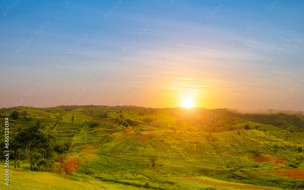 Landscape view of green grass with nive hills and mountain at sunset sky background.