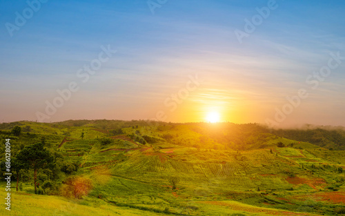 Landscape view of green grass with nive hills and mountain at sunset sky background.
