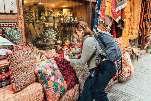 Woman taking photo of traditional ornamental pillows at market © julio