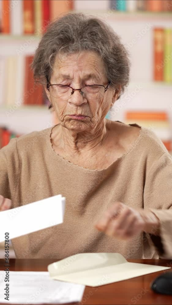 Vertical video of angry stressed elderly old woman 80s, opening envelope reading bad news in mail letter. Mad female feels frustrated by high bills, bank debt, tax invoice or mistake. Vertical video of angry stressed elderly old woman 80s, opening envelope reading bad news in mail letter. Mad female feels frustrated by high bills, bank debt, tax invoice or mistake.