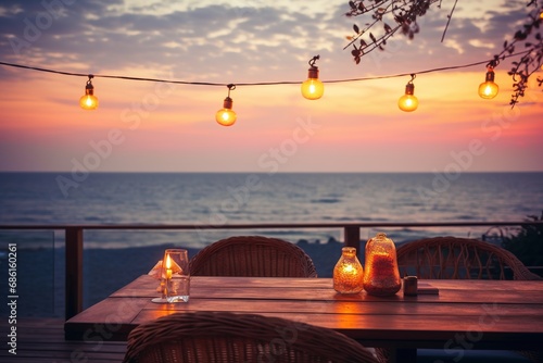 Outdoor restaurant at the beach. Tables at beach restaurant. Led light candles and wooden tables, chairs under beautiful sunset sky, sea view. Luxury hotel or resort restaurant 