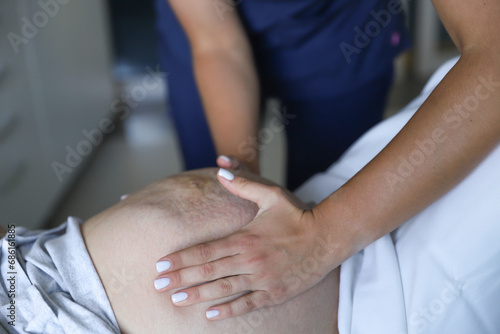 Hands of a young girl doctor who feel the belly of a pregnant girl first birth pregnancy doctor