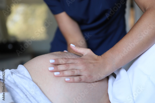 Hands of young doctor examining patient pregnant in ninth month childbirth delivery ward