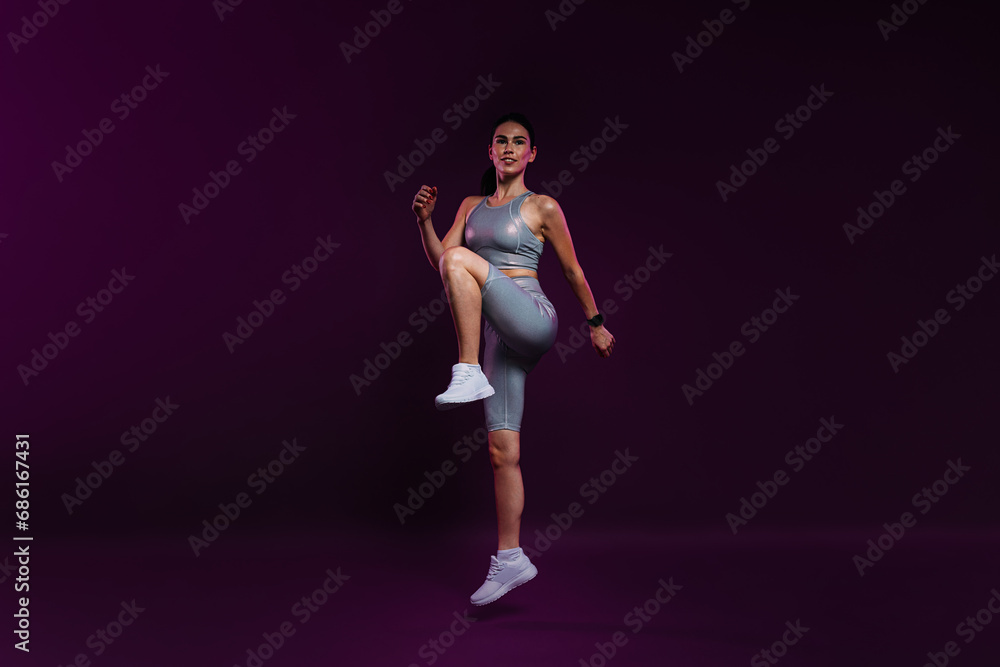 Full length of a slim female warming up her body against a magenta backdrop in the studio Full length of a slim female warming up her body against a magenta backdrop in the studio