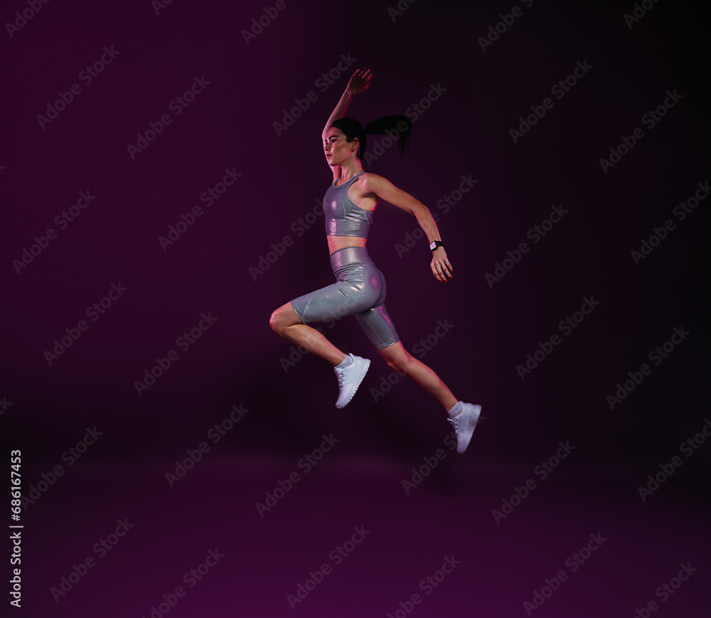 Full length of slim woman jumping against magenta backdrop