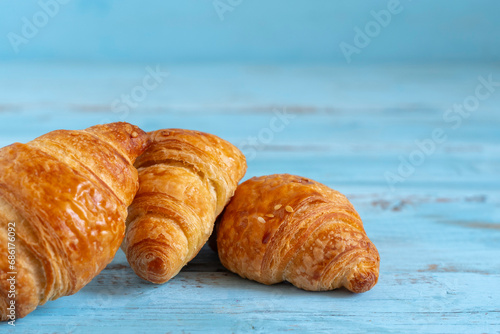 Fresh croissant for tasty breakfast on blue wooden background.