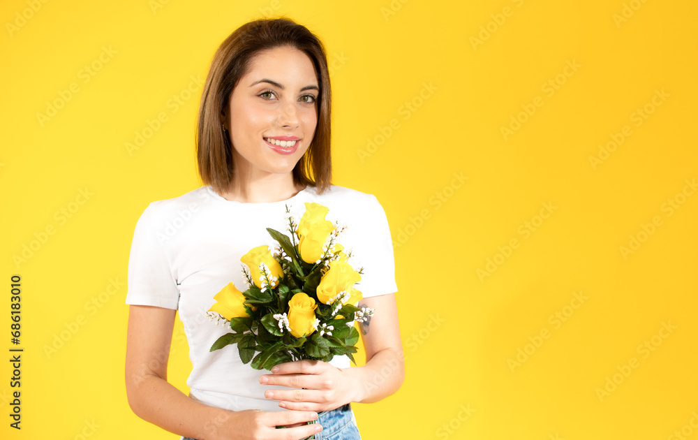 Portrait of a beautiful young girl holding big bouquet of irises and tulips isolated over yellow background