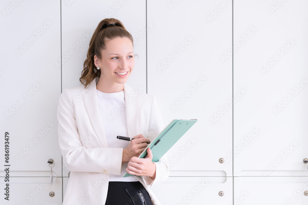 Beautiful and smiling businesswoman with paperwork in her hands standing in the office. Beautiful and smiling businesswoman with paperwork in her hands standing in the office.
