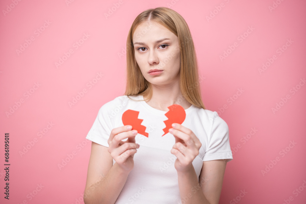 Beautiful girl on pink background with red broken heart. Concept of breakup, quarrel, divorce, unrequited love. Beautiful girl on pink background with red broken heart. Concept of breakup, quarrel, divorce, unrequited love.