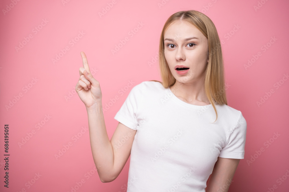 A cute girl stands on a pink background and points to a place for text. Banner or advertising layout. A cute girl stands on a pink background and points to a place for text. Banner or advertising layout.