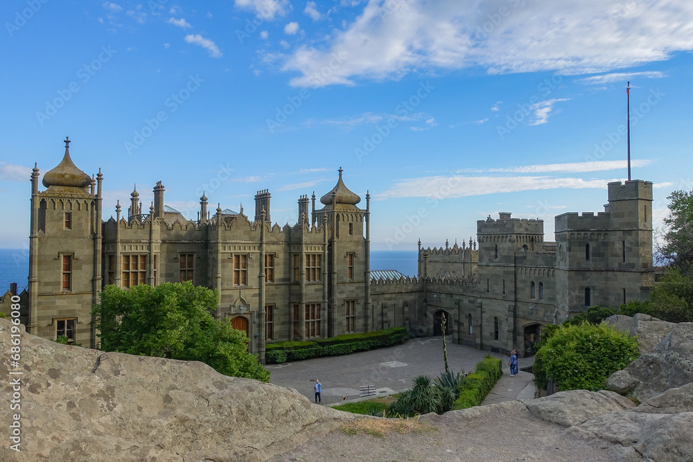Vorontsov Palace in Crimea in summer. Ancient walls with many columns, turrets and domes. An architectural masterpiece, the legacy of the ancestors. Green trimmed bushes
