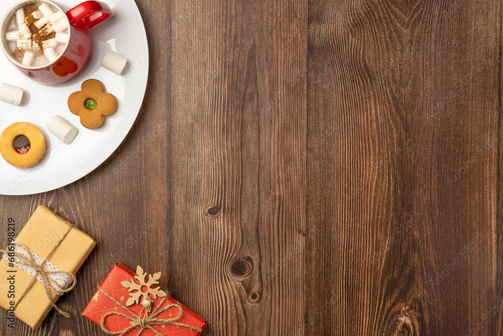 Plate with cookies and mug of hot chocolate with marshmallows and Christmas gift boxes on wooden background. Space for text. Plate with cookies and mug of hot chocolate with marshmallows and Christmas gift boxes on wooden background. Space for text.