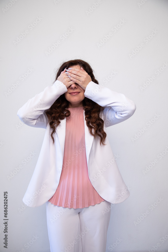 Beautiful brunette woman covering her eyes with her hands on a white background Beautiful brunette woman covering her eyes with her hands on a white background