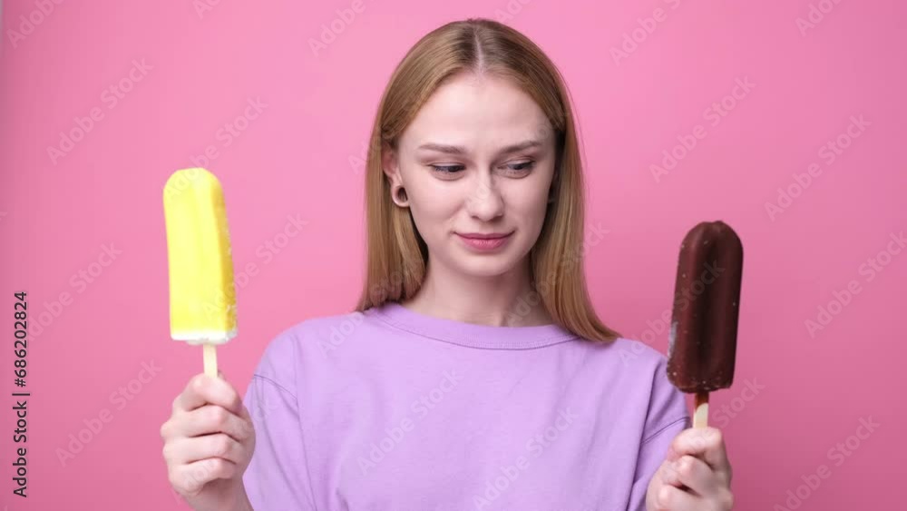 Happy young woman eating yellow ice cream on pink background. Concept of summer and sweet cold desserts. Happy young woman eating yellow ice cream on pink background. Concept of summer and sweet cold desserts.